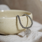 Silver Kāpehu Whetū Beaded Bracelet sitting in a clay jewellery bowl